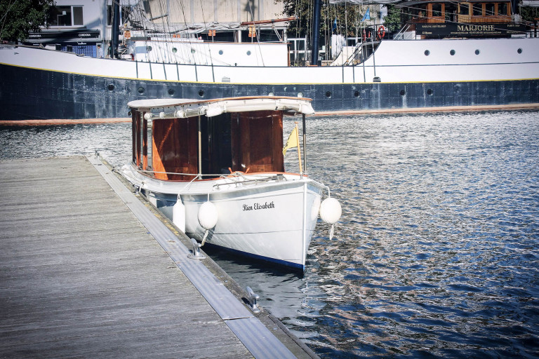 A front view of Rondvaarten Eilandje's authentic notary boat docked in the city harbor of Antwerp